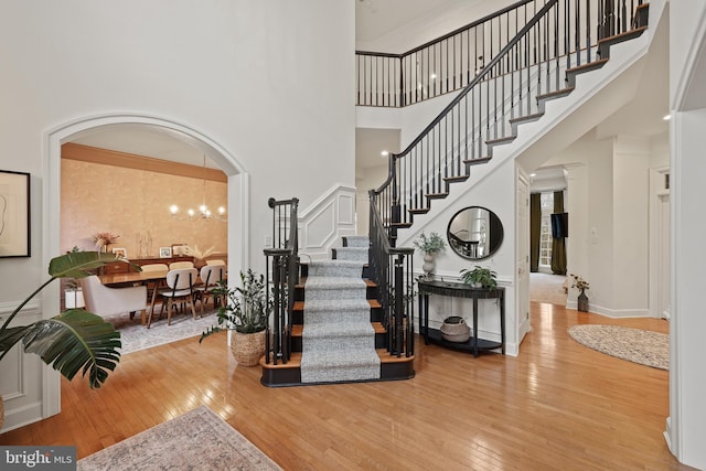 entryway featuring a notable chandelier, wood-type flooring, and a high ceiling