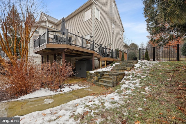 snow covered rear of property featuring a deck