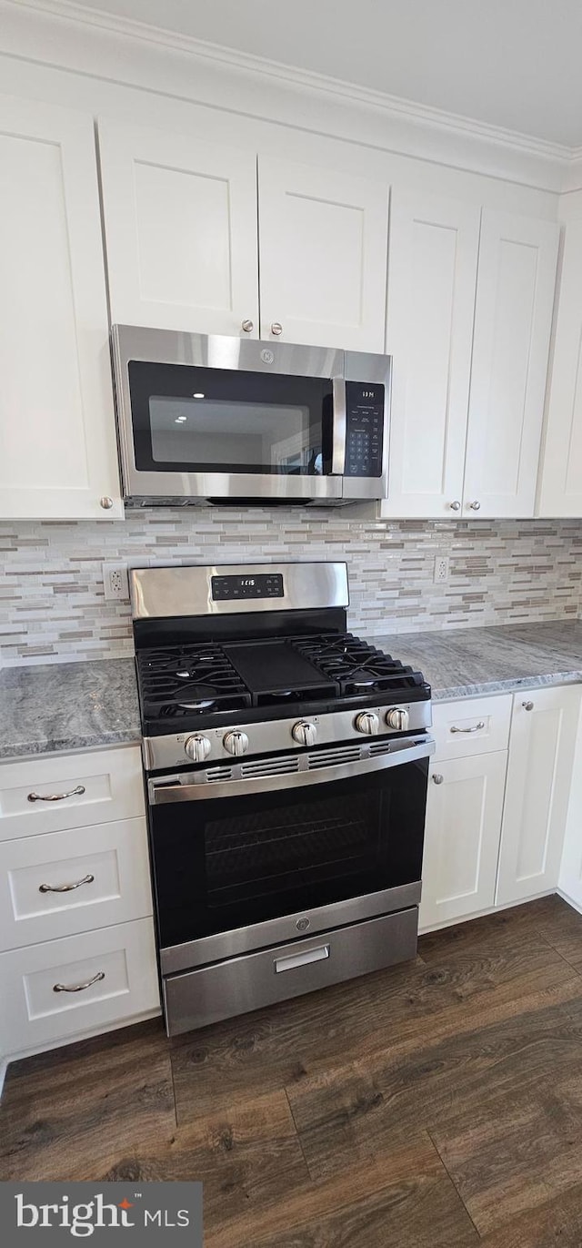 kitchen featuring stainless steel appliances, white cabinetry, and light stone countertops