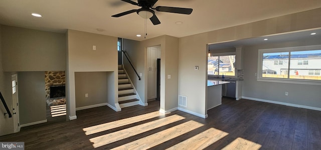 unfurnished living room with ceiling fan, dark wood-type flooring, sink, and a fireplace