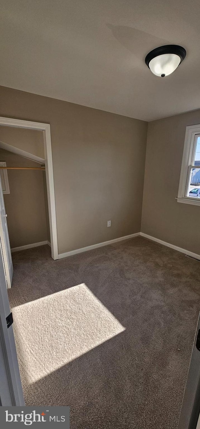 unfurnished bedroom featuring dark carpet and a closet