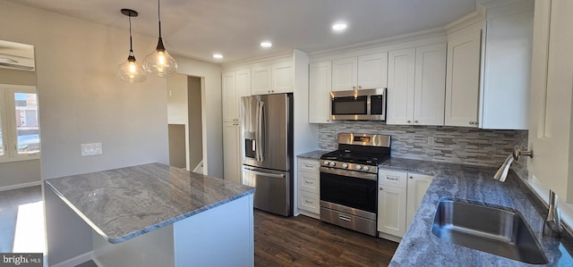 kitchen with sink, white cabinets, tasteful backsplash, hanging light fixtures, and appliances with stainless steel finishes