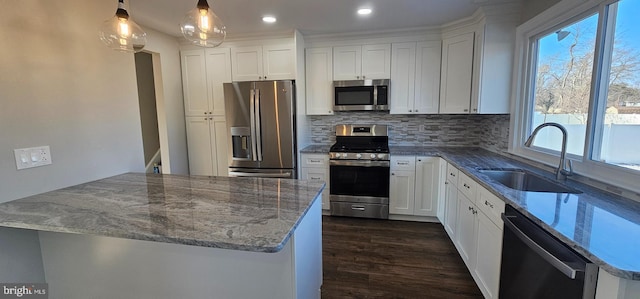 kitchen featuring appliances with stainless steel finishes, hanging light fixtures, white cabinets, and sink