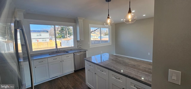 kitchen featuring dishwasher, hanging light fixtures, white cabinetry, dark stone countertops, and sink