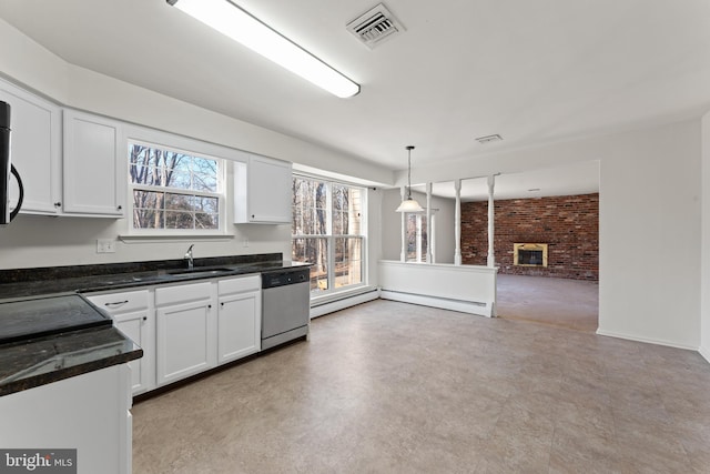 kitchen featuring stainless steel dishwasher, hanging light fixtures, brick wall, white cabinetry, and sink