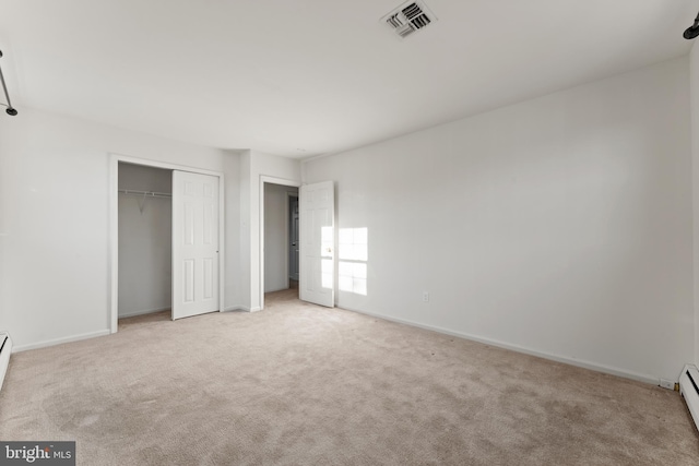 unfurnished bedroom with a baseboard radiator, a closet, and light carpet