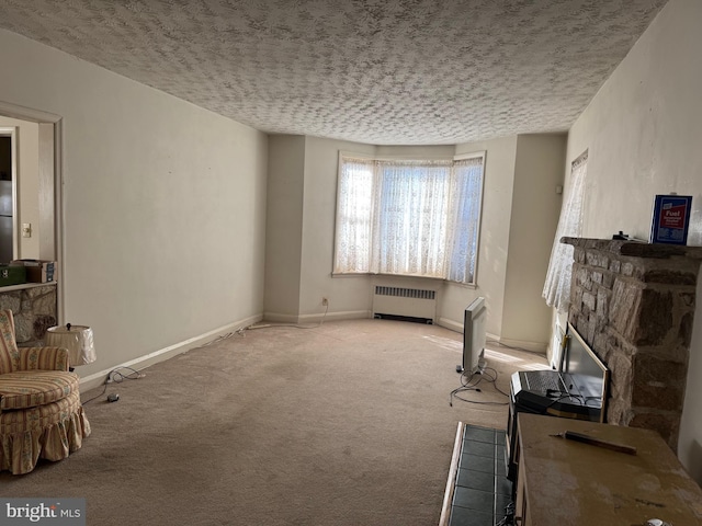 carpeted living room featuring a textured ceiling, a stone fireplace, and radiator