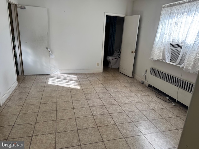 unfurnished bedroom featuring cooling unit, radiator, and light tile patterned floors