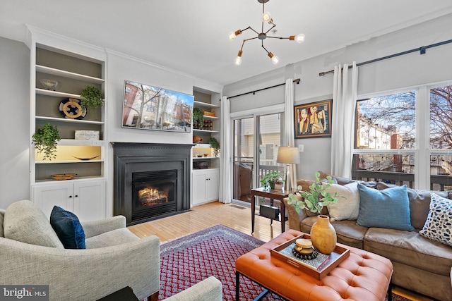 living room with built in features, light wood-type flooring, and a chandelier