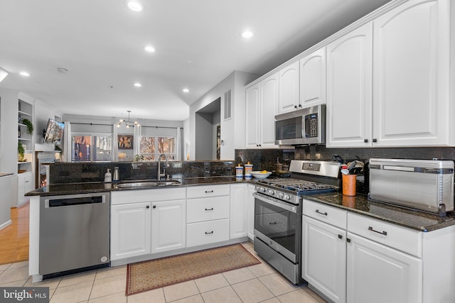 kitchen featuring pendant lighting, white cabinets, appliances with stainless steel finishes, sink, and kitchen peninsula