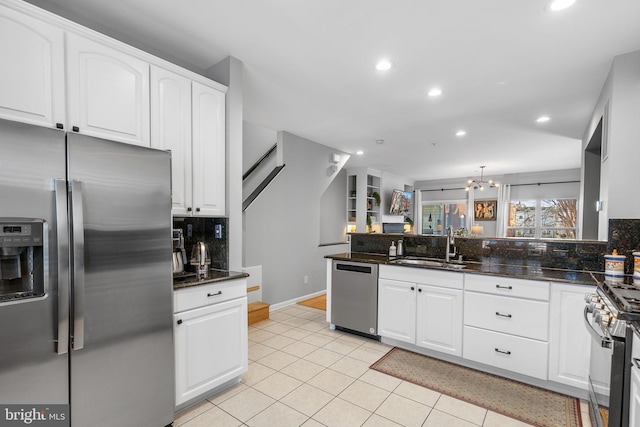 kitchen featuring white cabinets, appliances with stainless steel finishes, dark stone countertops, tasteful backsplash, and sink