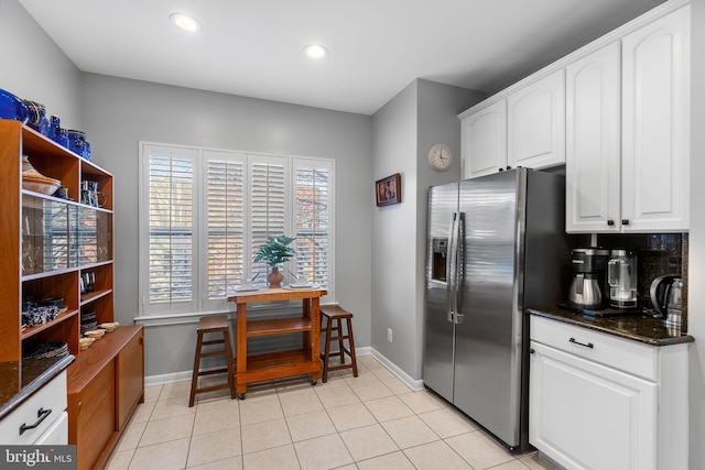 kitchen with backsplash, white cabinets, stainless steel fridge with ice dispenser, and dark stone counters