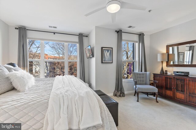 bedroom featuring multiple windows, light colored carpet, and ceiling fan