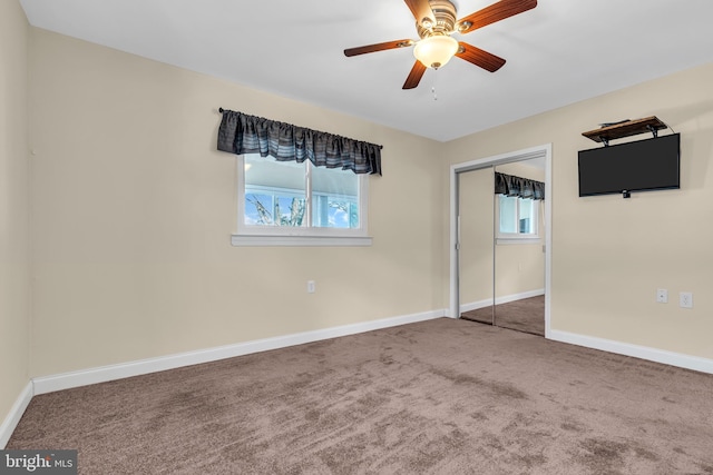 unfurnished bedroom featuring multiple windows, carpet floors, a closet, and ceiling fan