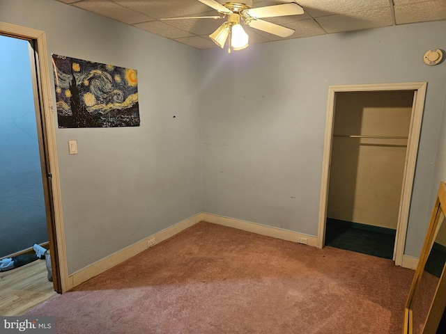 unfurnished bedroom with carpet flooring, a paneled ceiling, ceiling fan, and a closet