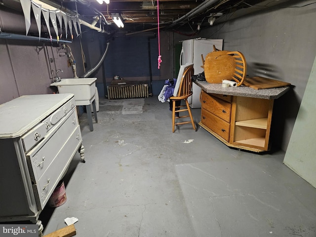 basement featuring sink and white refrigerator