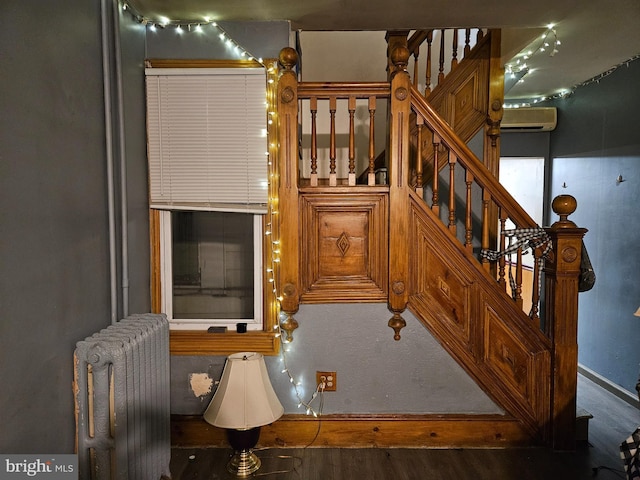 stairway with hardwood / wood-style flooring, an AC wall unit, and radiator