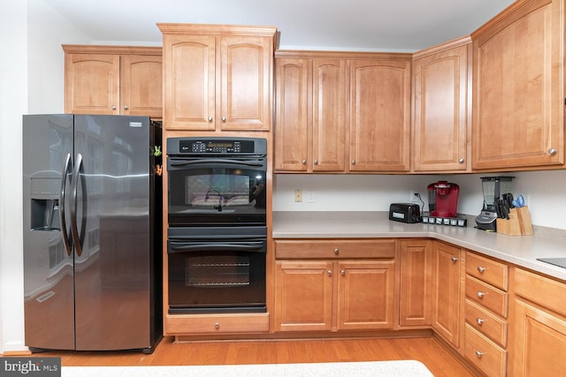 kitchen featuring light hardwood / wood-style floors, stainless steel fridge with ice dispenser, and double oven