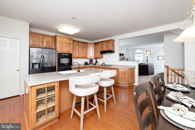 kitchen featuring stovetop, sink, light hardwood / wood-style floors, and fridge with ice dispenser