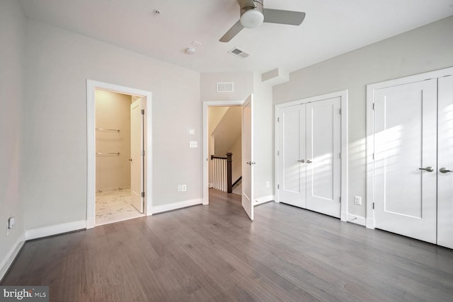 unfurnished bedroom with two closets, hardwood / wood-style flooring, ceiling fan, and ensuite bathroom