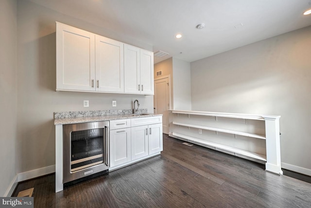 bar featuring dark wood-type flooring, white cabinets, sink, wine cooler, and light stone counters