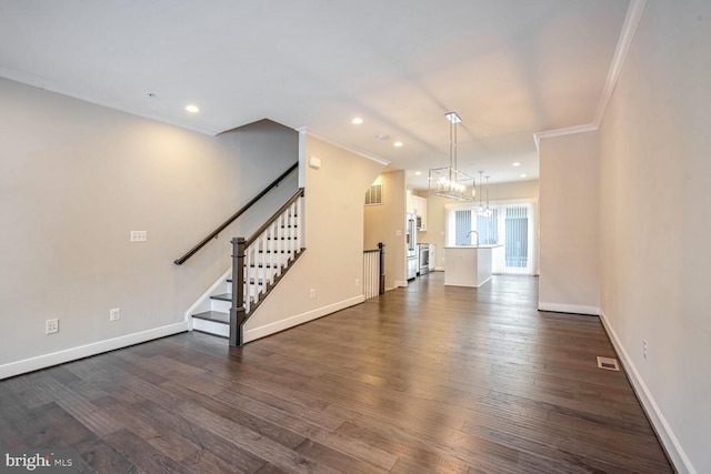 unfurnished living room featuring dark hardwood / wood-style flooring, ornamental molding, sink, and an inviting chandelier