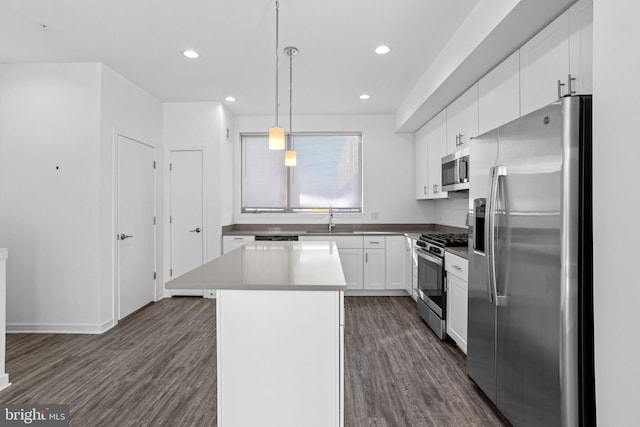 kitchen with sink, hanging light fixtures, stainless steel appliances, a kitchen island, and white cabinets