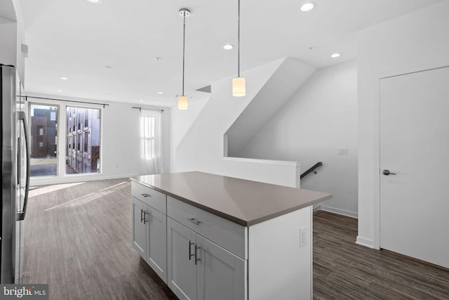 kitchen featuring dark wood-type flooring, stainless steel fridge, a center island, and hanging light fixtures