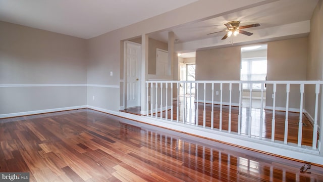 spare room with baseboards, ceiling fan, and wood finished floors