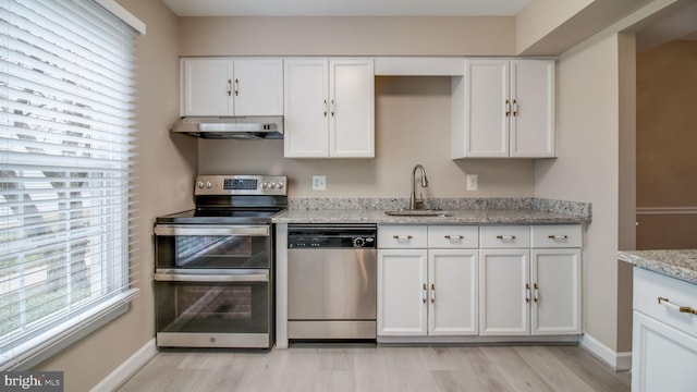 kitchen featuring under cabinet range hood, light wood-type flooring, white cabinets, stainless steel appliances, and a sink