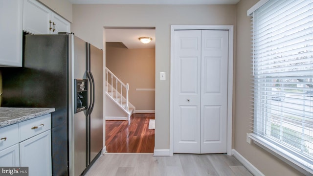 kitchen featuring white cabinetry, light wood-type flooring, baseboards, and stainless steel fridge with ice dispenser