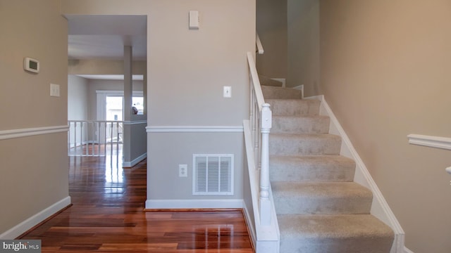 stairs featuring wood finished floors, visible vents, and baseboards