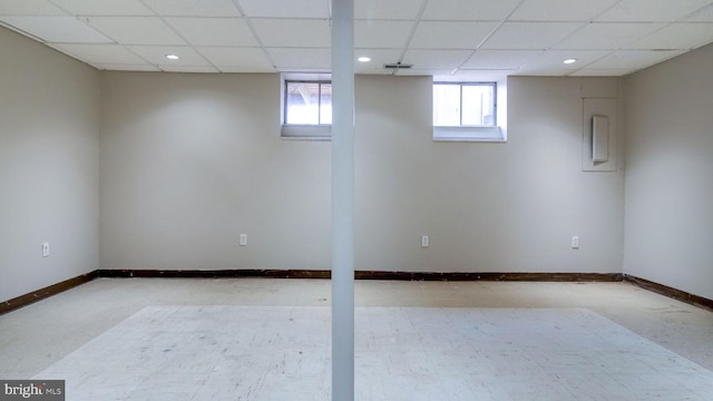 below grade area with a drop ceiling, visible vents, and baseboards