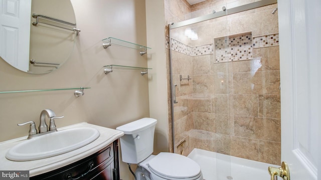 bathroom with vanity, a shower stall, and toilet