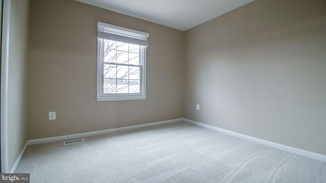 unfurnished room with baseboards, visible vents, and light carpet