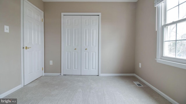 unfurnished bedroom featuring visible vents, baseboards, carpet, and a closet