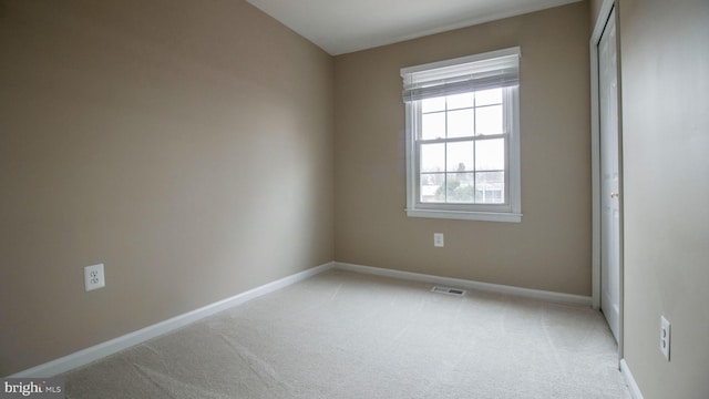 unfurnished bedroom featuring visible vents, baseboards, light colored carpet, and a closet