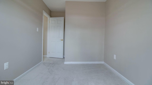 unfurnished room featuring baseboards and light carpet