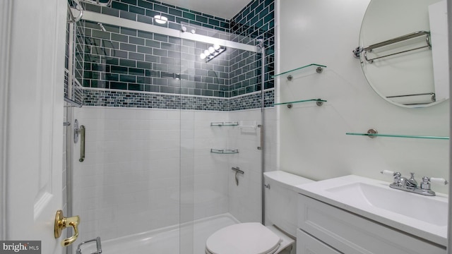 bathroom featuring vanity, a shower stall, and toilet