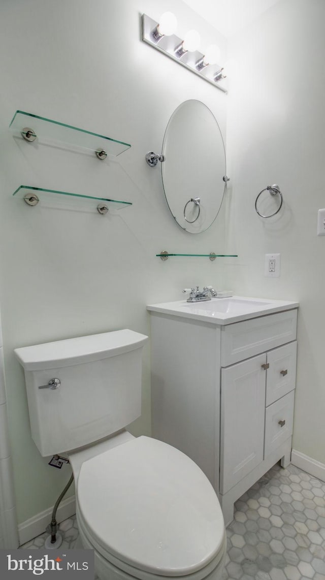 bathroom featuring toilet, vanity, and baseboards