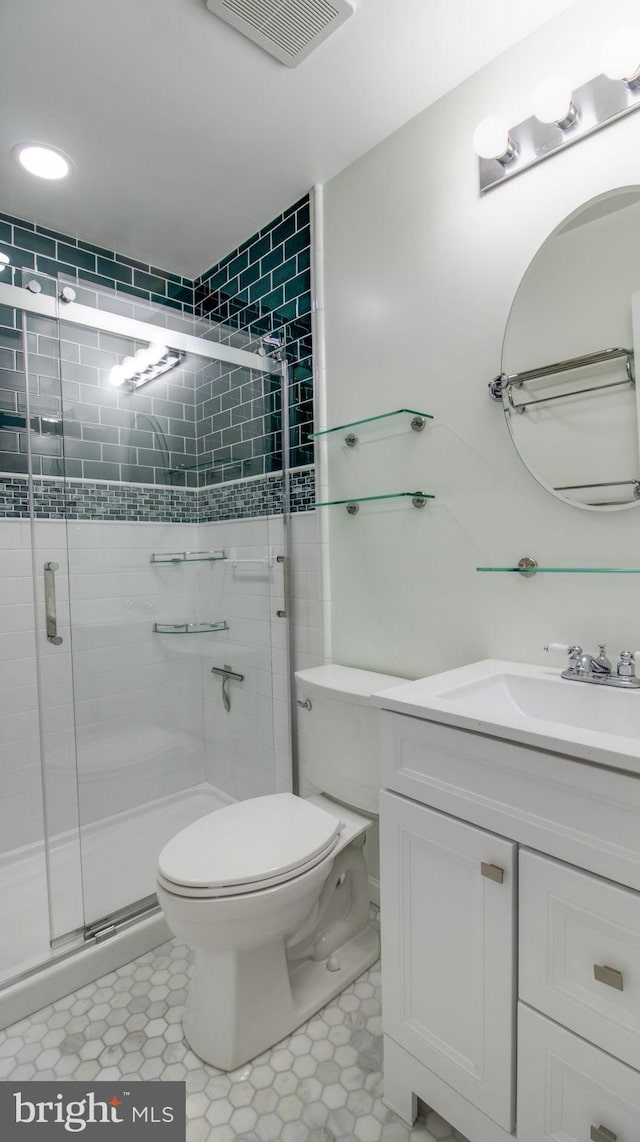 bathroom featuring visible vents, a shower stall, toilet, and vanity