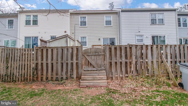 rear view of property with a fenced backyard and a gate