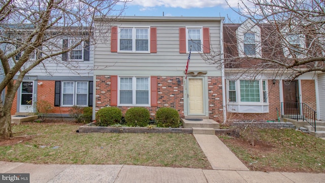 townhome / multi-family property featuring a front lawn and brick siding