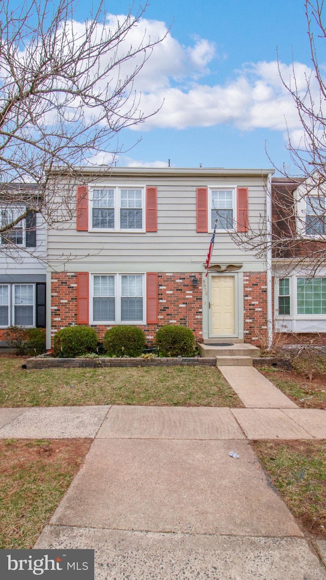 view of property featuring a front lawn and brick siding