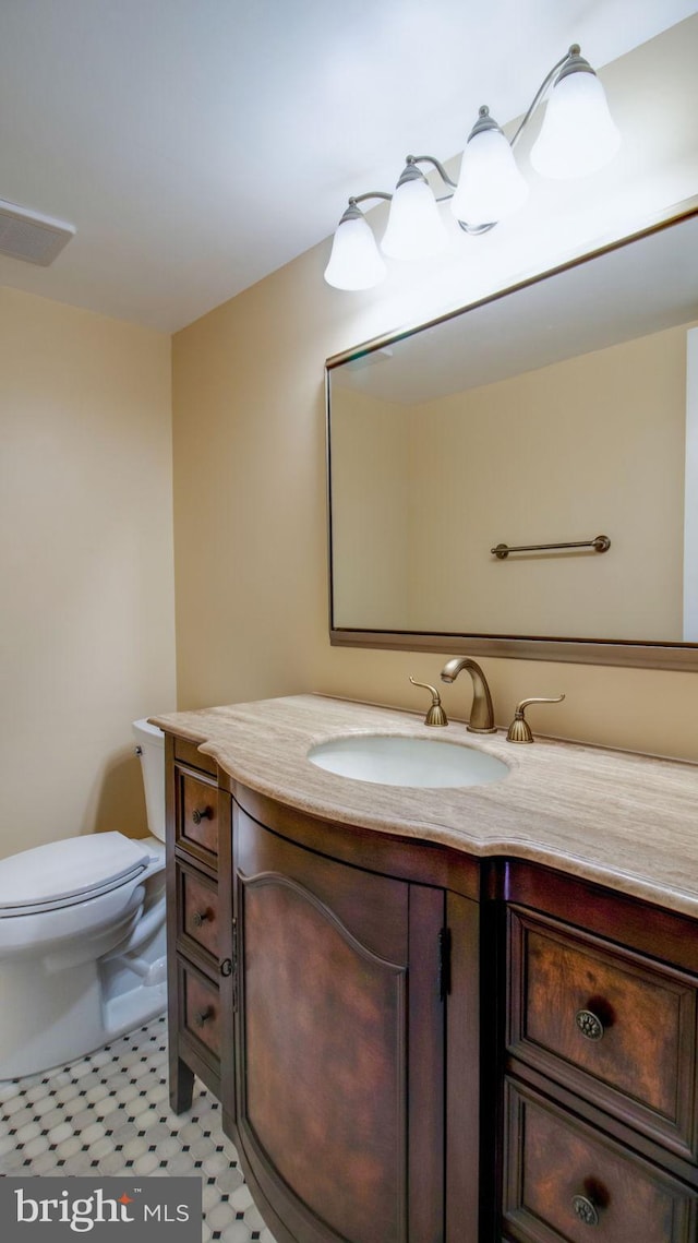 half bathroom with vanity, toilet, and visible vents