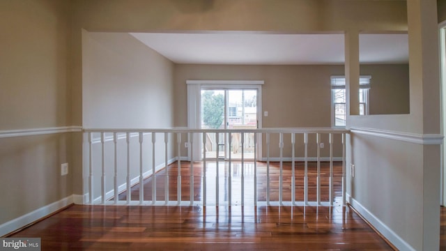 corridor with baseboards and wood finished floors