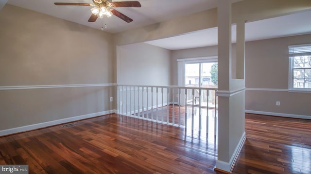 unfurnished room with a wealth of natural light, baseboards, wood finished floors, and a ceiling fan