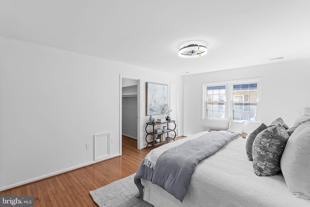 bedroom with hardwood / wood-style floors and a walk in closet