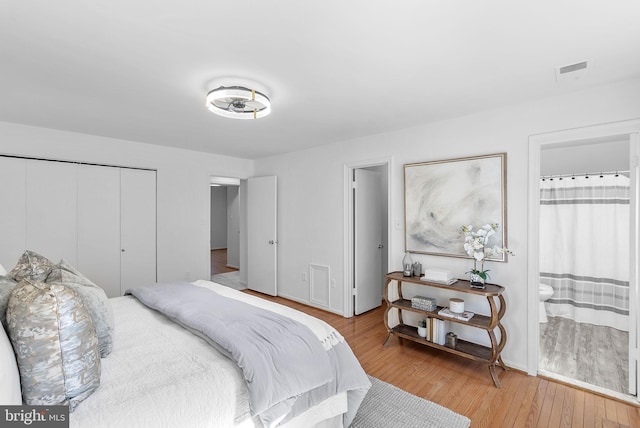 bedroom with hardwood / wood-style flooring, connected bathroom, and a closet