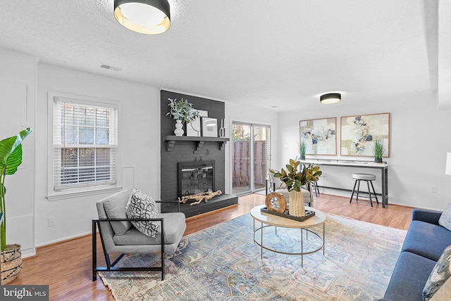 living room with hardwood / wood-style flooring, a textured ceiling, and a fireplace